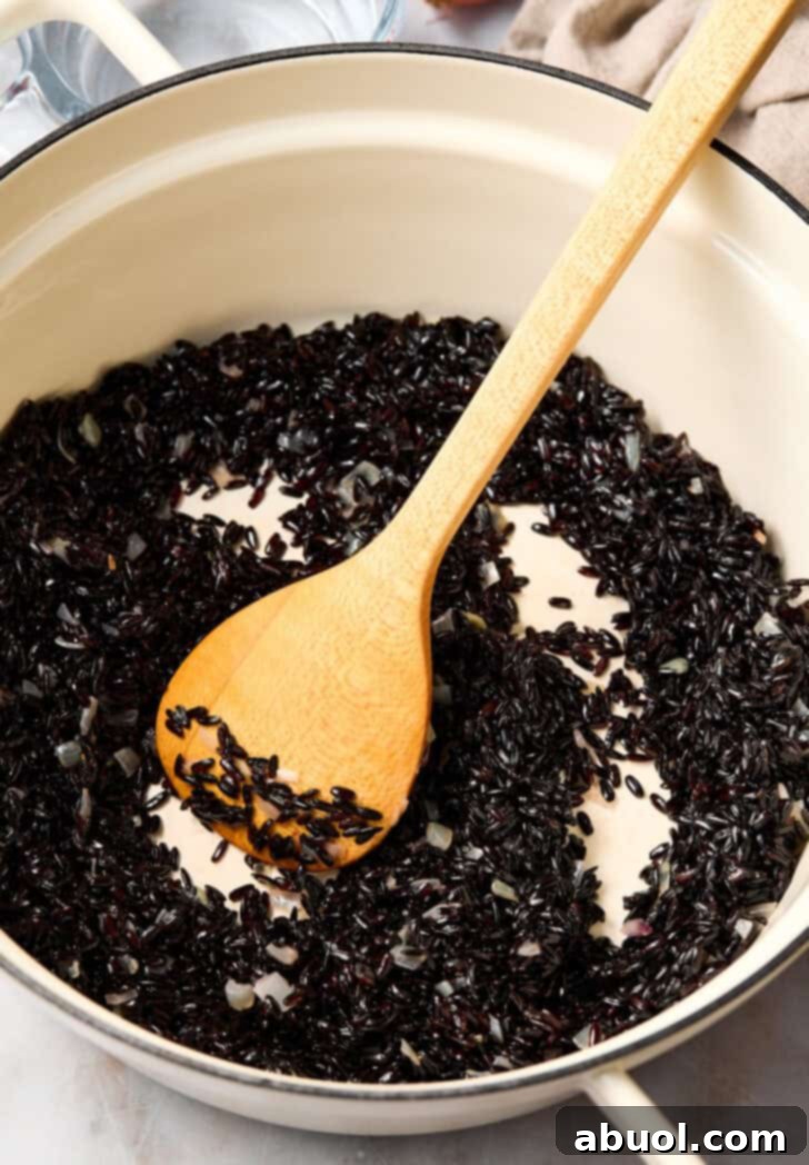 Black rice simmering gently in a pot on the stovetop.