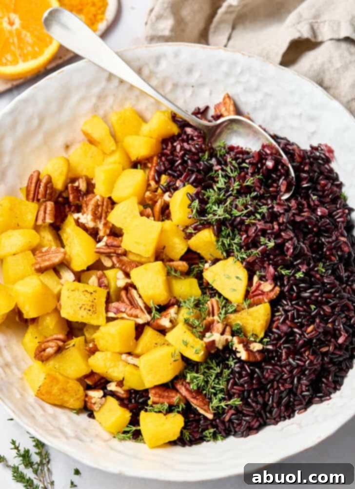 Close-up of a serving spoon mixing roasted acorn squash and pecans into cooked forbidden black rice.