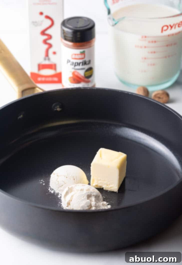 A black skillet with two small scoops of flour and a large cube of flour.