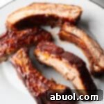 Five air fried baby back ribs on a white plate, showcasing the final delicious dish.