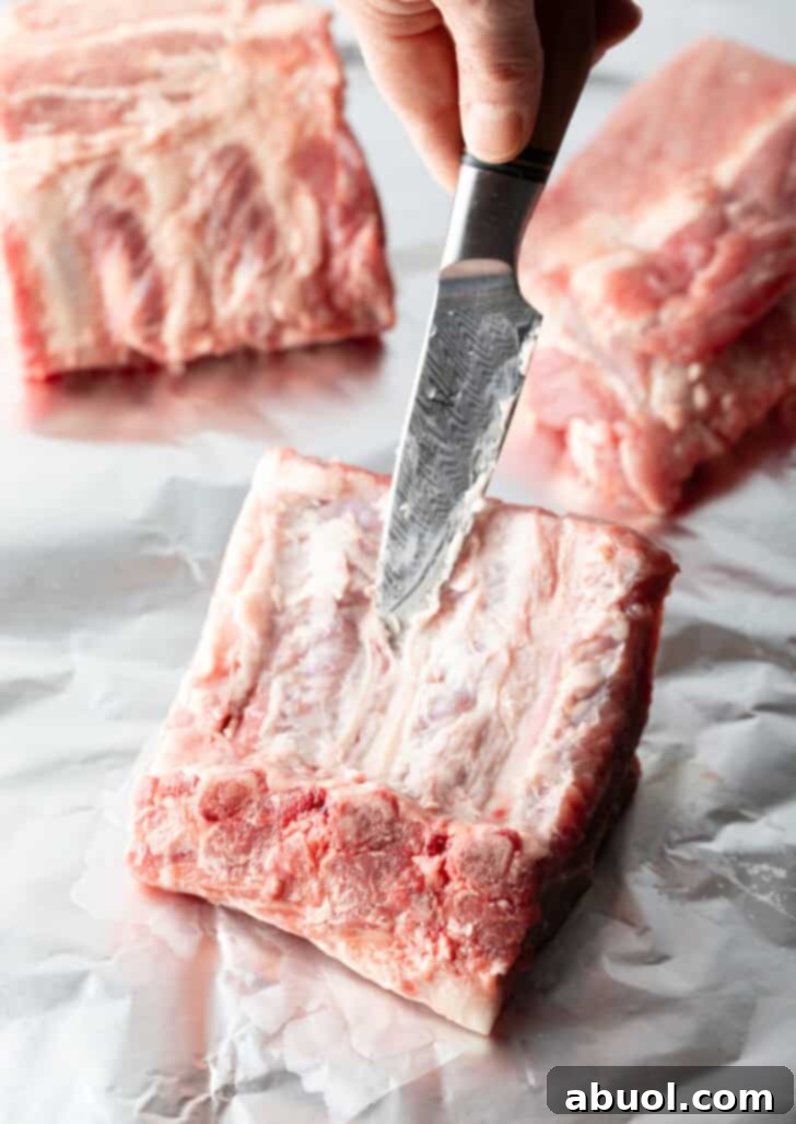 Cutting a rack of 4 baby back ribs into individual ribs for easier handling and cooking.
