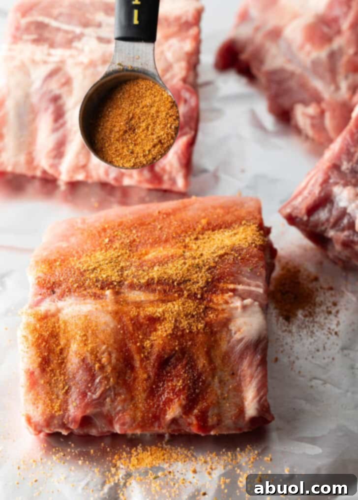 A small rack of baby back ribs perfectly coated in a generous layer of seasoning rub, ready for cooking.