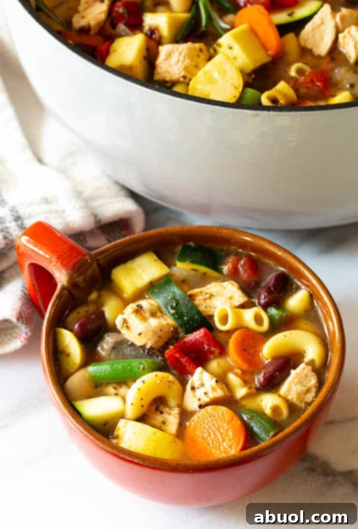 A top-down view of a large, handle-equipped mug, brimming with delicious chicken minestrone soup, ready to be savored.