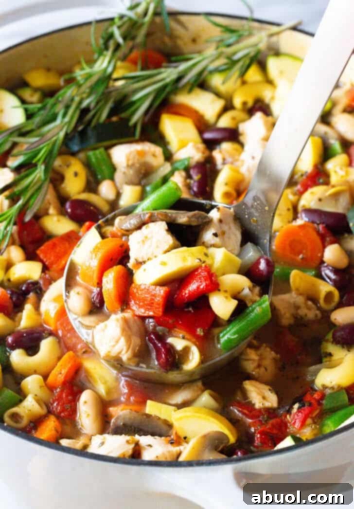 A ladle serving a generous portion of vibrant chicken and vegetable minestrone soup into a bowl, showcasing its rich texture and ingredients.