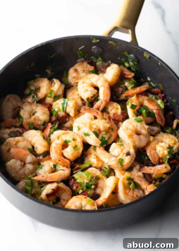 A cast iron skillet filled with beautifully cooked shrimp, glistening with flavorful seasoning and ready to be served. The rich color suggests perfect doneness and delicious taste.