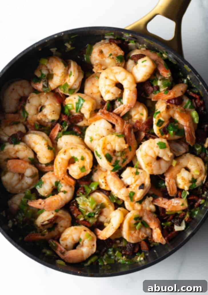 A top-down view of a cast iron skillet showcasing perfectly cooked shrimp, ready to be paired with creamy grits. The vibrant colors and enticing texture promise a delicious meal.