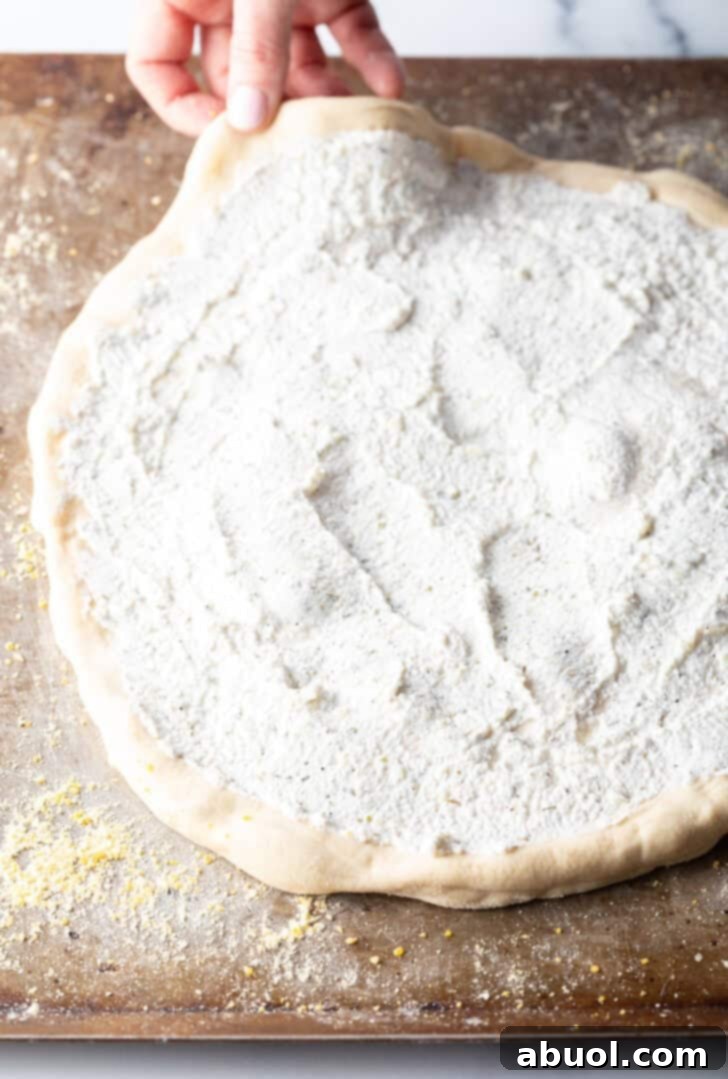 Unbaked pizza topped with white sauce.