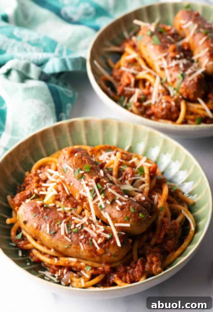 Green bowl with Sunday gravy pasta with meat sauce and sausages.