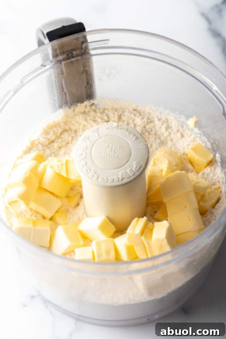 Dry ingredients (flour, salt, sugar) and chunks of cold butter and shortening in a food processor bowl, ready for pulsing to combine.