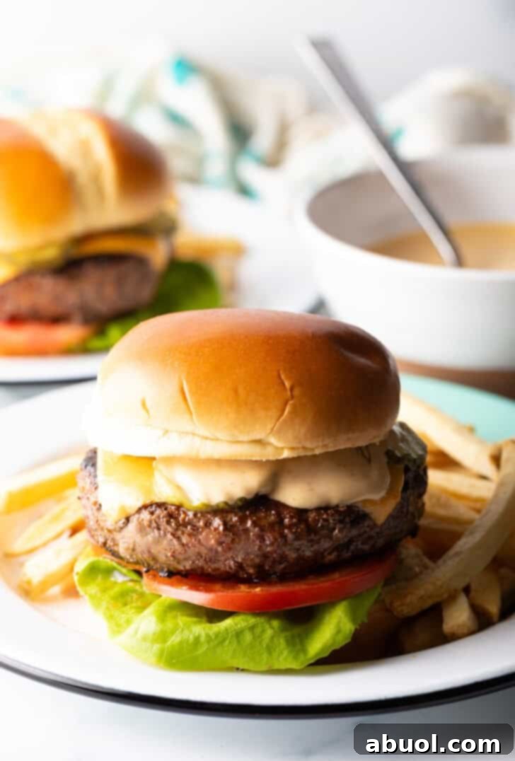 A perfectly cooked cheeseburger adorned with melted cheese, lettuce, and tomato, served alongside a pile of golden french fries.