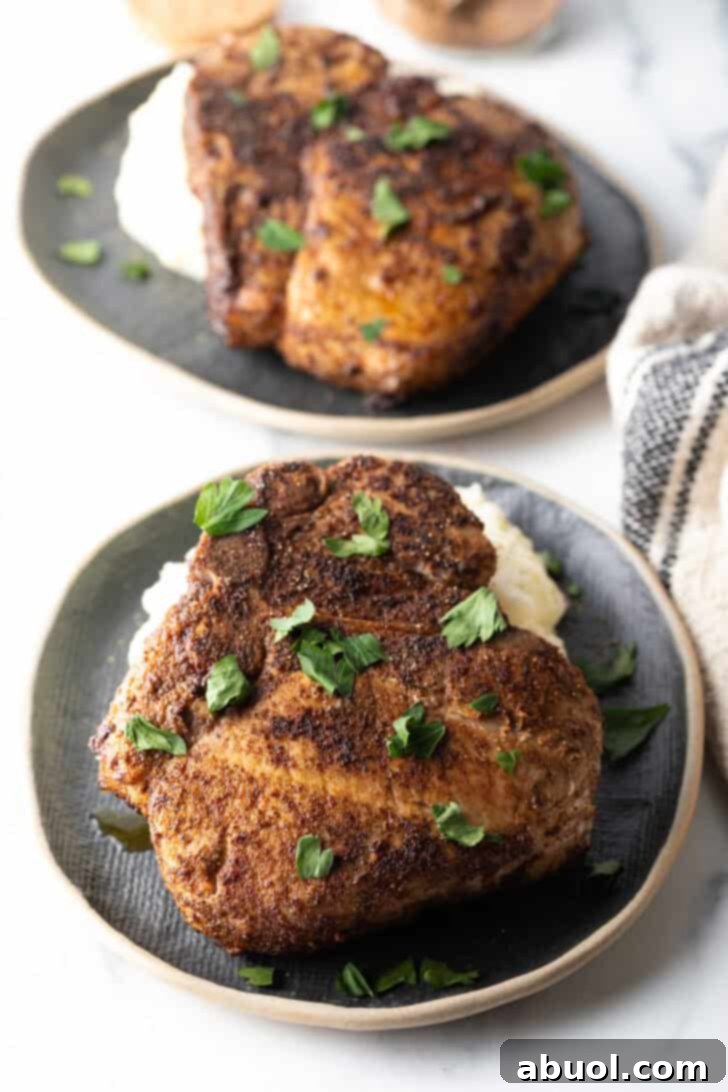 Browned seasoned bone-in pork chop on a plate, garnished with chopped parsley.