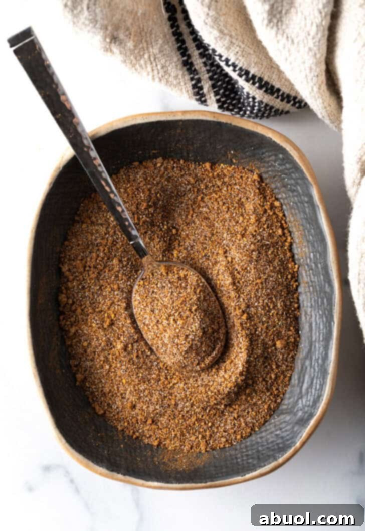 Top down view blend of spices in an oval dish with metal spoon.