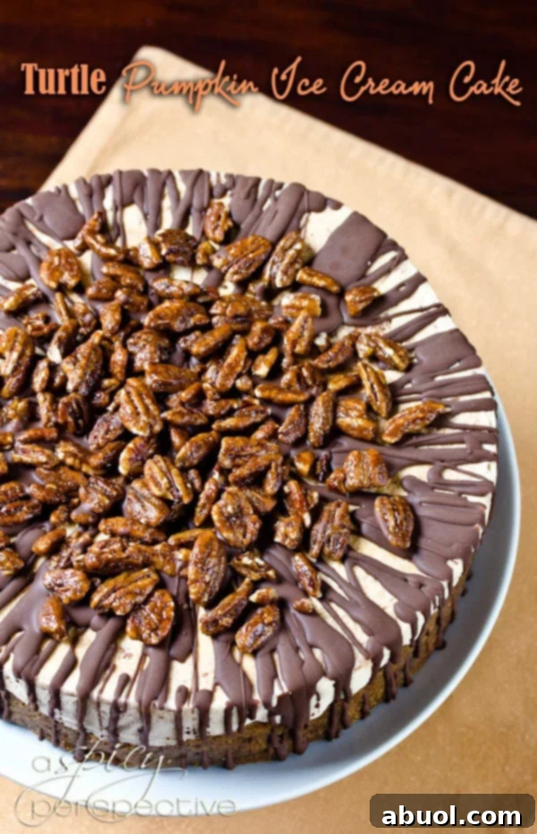 A slice of Turtle Pumpkin Ice Cream Cake on a plate, showcasing its layers of gingersnap crust, dulce de leche, pumpkin ice cream, chocolate shell, and candied pecans.