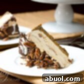 A slice of Turtle Pumpkin Ice Cream Cake on a plate, showcasing its layers of gingersnap crust, dulce de leche, pumpkin ice cream, chocolate shell, and candied pecans.