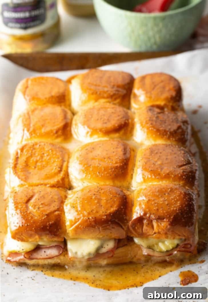 Sweet Hawaiian Bites 11 A panoramic shot of a dozen freshly baked ham and cheese sliders, made with King's Hawaiian rolls, glistening with honey butter.