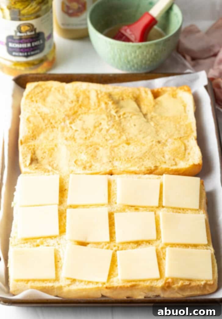 Sweet Hawaiian Bites 7 The process of making Hawaiian sliders, showing the bottom layer of sweet rolls topped with slices of white cheddar cheese.