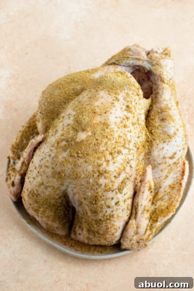 A raw turkey, generously coated with a homemade spice blend, ready for the deep fryer.
