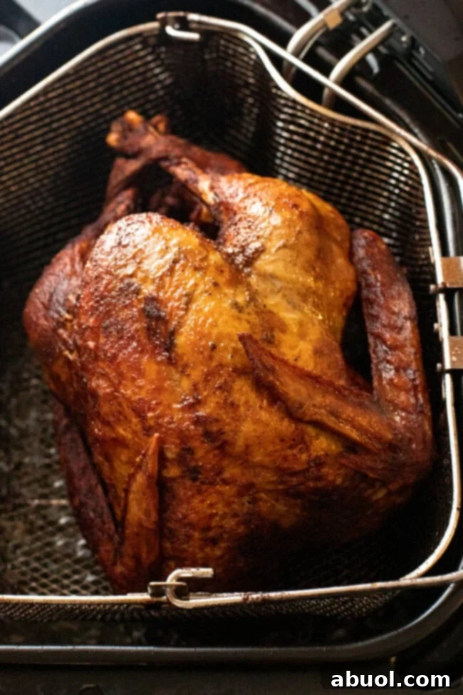 A freshly deep-fried turkey in its fry basket, removed from the oil, showing its beautiful golden-brown color and crispy texture.