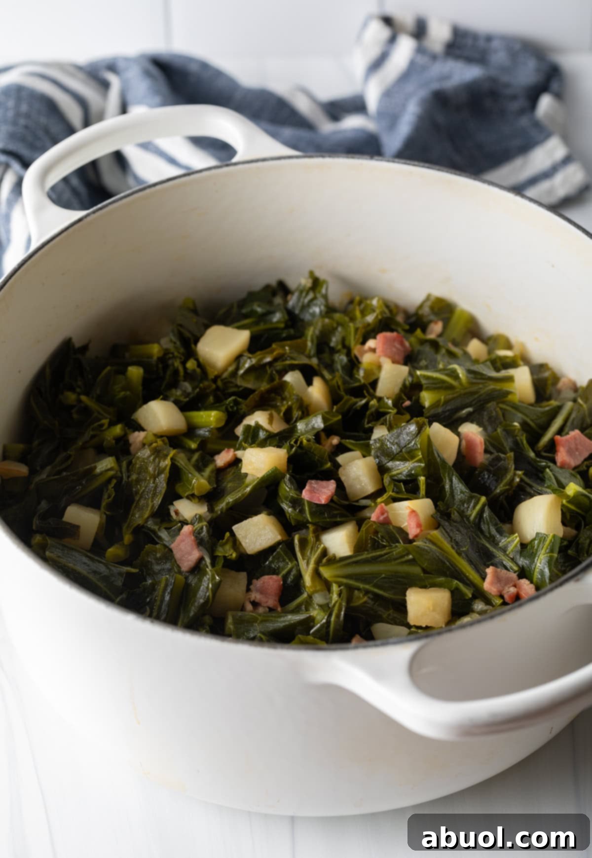 A large Dutch oven filled with a generous serving of perfectly finished collard greens, ready to be enjoyed as a hearty Southern meal.