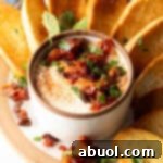 White cup with whipped feta with chopped sun dried tomato, on a plate surrounded by slices of toasted baguette.
