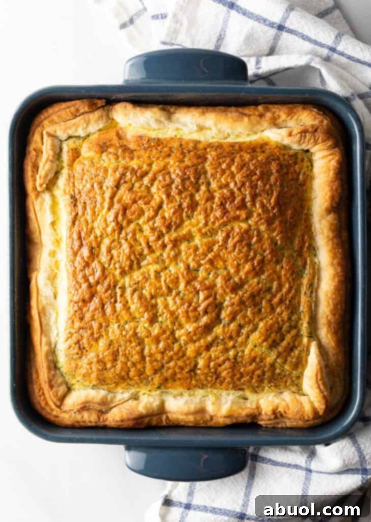 A top-down view of the square baking dish filled with the easy egg bake breakfast casserole, ready for the oven, showcasing its smooth surface.
