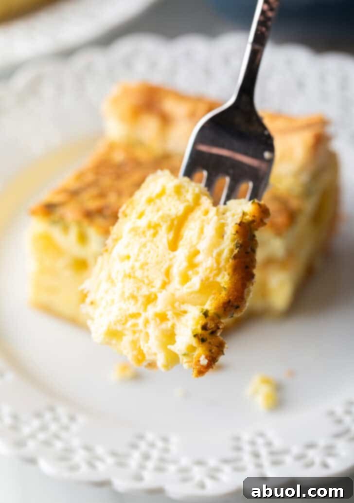 A fork lifts a perfect bite of fluffy egg casserole towards the camera, highlighting its delicious texture.