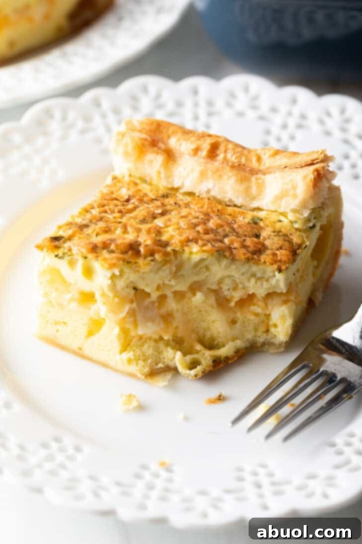 A single square serving of the fluffy egg casserole rests on a pristine white plate, accompanied by a fork, ready to be enjoyed.
