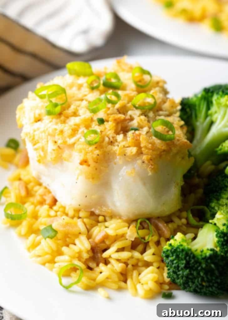 Crispy potato chip crusted baked sea bass served beautifully on a plate with fluffy yellow rice and tender, vibrant cooked broccoli, showcasing a complete and appetizing meal.