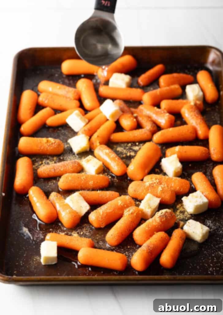 Baking sheet with baby carrots and cubes of butter.
