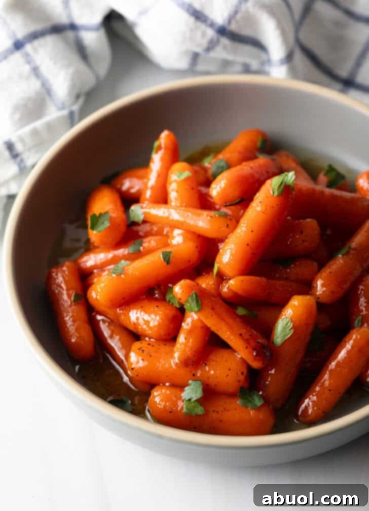 Bowl of glazed honey baby carrots sprinkled with chopped parsley.