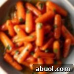 Top down bowl of glazed honey baby carrots sprinkled with chopped parsley.
