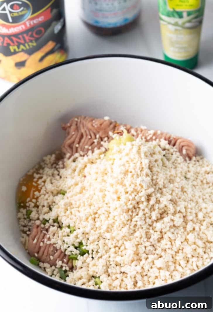 Ground turkey in a white bowl, lightly covered with crispy panko breadcrumbs, ready for mixing.