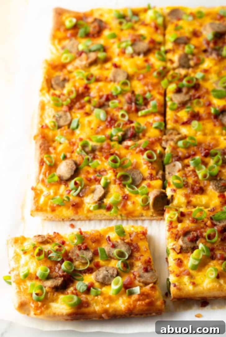 A rectangular baking sheet tray showcasing a loaded breakfast pizza with cheese, sausage, and vibrant green onions. The pizza has been neatly sliced into 8 rectangular portions, with one piece partially removed, highlighting its generous toppings.