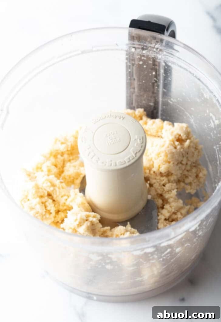 Processing butter and flour in a food processor to create pie dough.