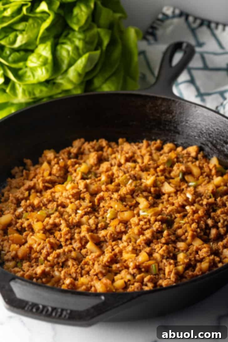 A black skillet filled with the completed ground chicken mixture, rich with hoisin and soy sauce, ready to be served.