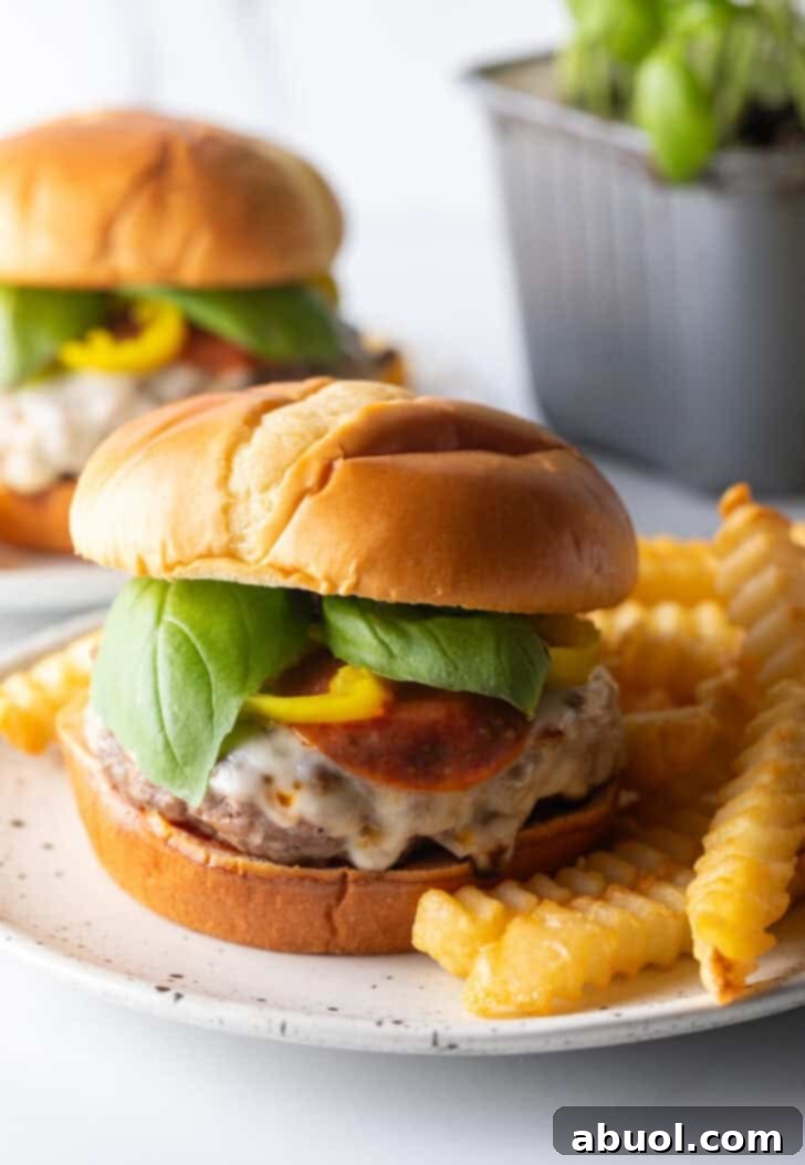 A delectable pizza burger served on a white and black speckled plate, accompanied by perfectly crinkle-cut french fries.