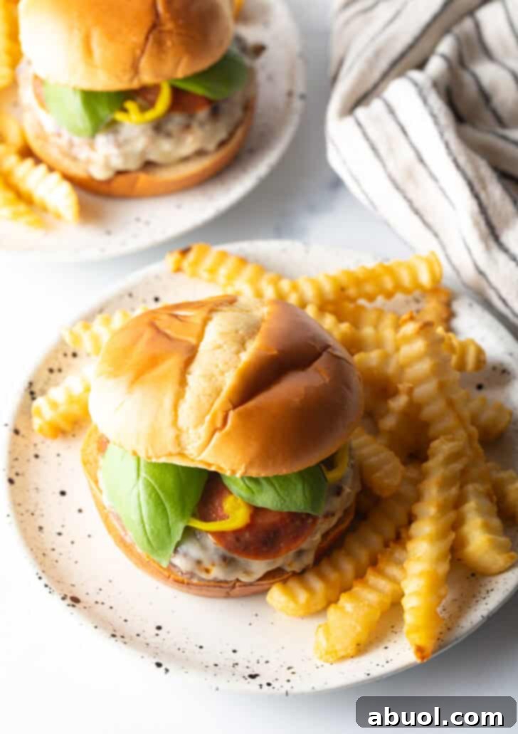 A mouth-watering pizza burger on a plate, perfectly paired with a generous serving of crispy french fries, inviting you to take a bite.