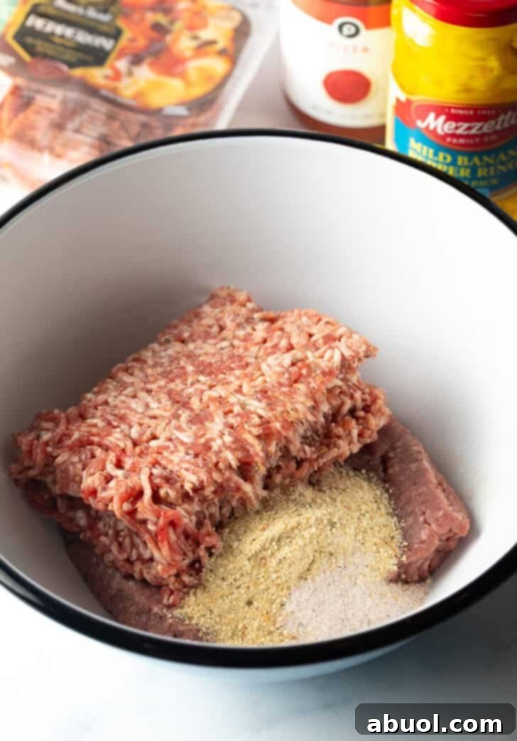 White mixing bowl filled with ground beef, breadcrumbs, and seasoning, ready to be combined for burger patties.