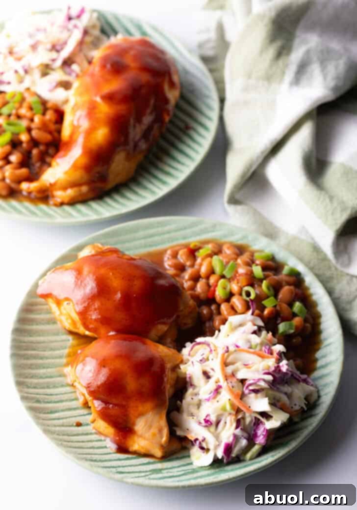 A vibrant green plate showcasing perfectly cooked BBQ chicken alongside creamy coleslaw and rich baked beans, creating a balanced and flavorful meal.