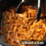 Barbecue Chicken in the Crock Pot, showing tongs ready to either serve whole pieces or shred the chicken for pulled sandwiches.
