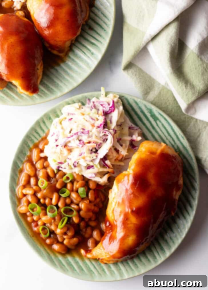 A vibrant top-down view of a green plate featuring a generous serving of BBQ chicken, fresh coleslaw, and savory baked beans, showcasing a complete and delicious meal.