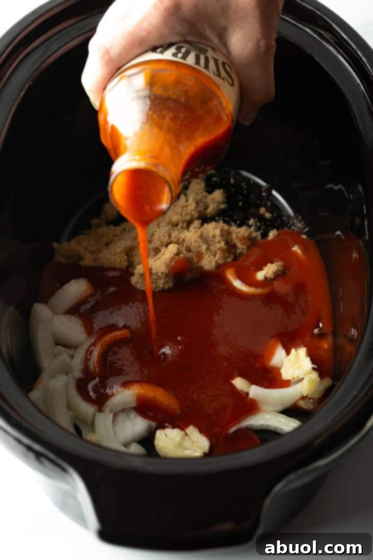 Pouring classic barbecue sauce from a bottle into a slow cooker, combining it with brown sugar and onion slices to create the sauce mixture.