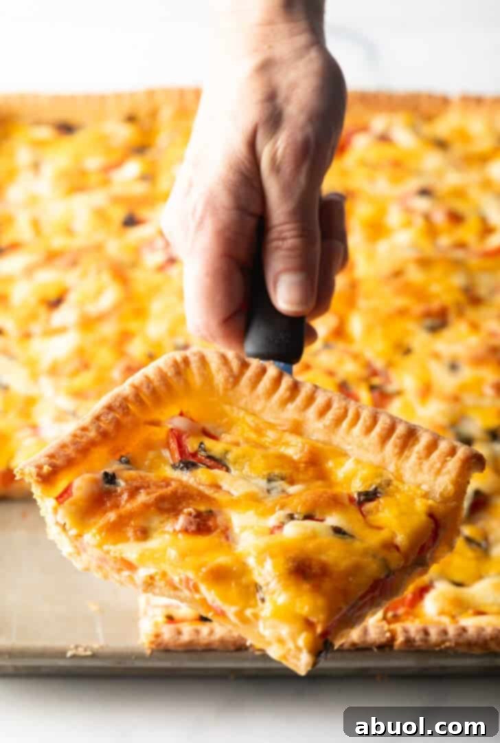 Fresh Garden Tomato Tart 2 Hand holding a spatula with a large corner square of southern tomato pie.