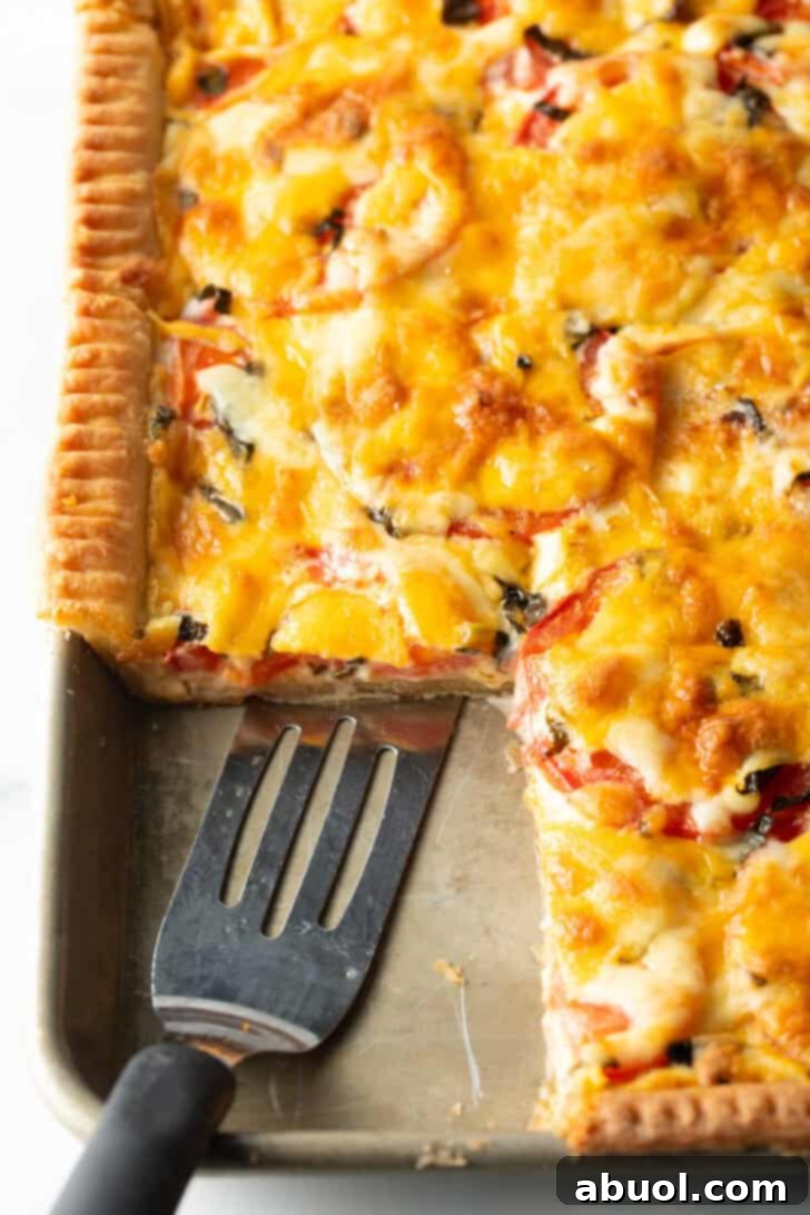 Fresh Garden Tomato Tart 4 Southern tomato slab pie with large square removed, and a slotted spatula in the pan.
