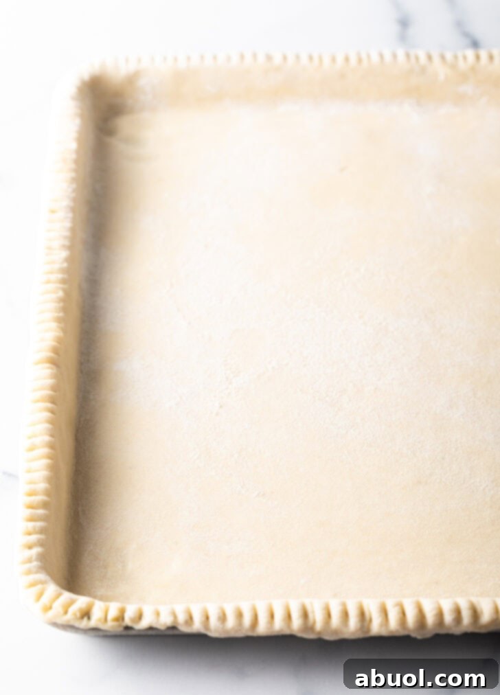 Fresh Garden Tomato Tart 8 Raw pie dough crimped around a large rectangle baking sheet.