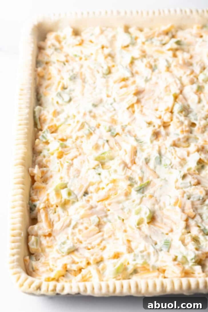 Fresh Garden Tomato Tart 9 A mixture of mayo, shredded cheese, and green onions covering a rectangle of raw pie dough.