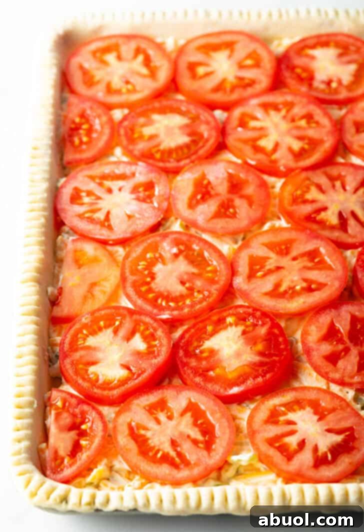 Fresh Garden Tomato Tart 10 Rows of raw tomato slices on top of an unbaked rectangle of pie dough.