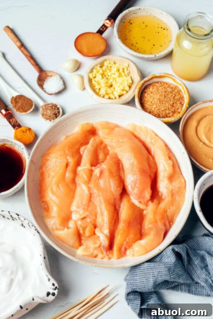 Pieces of chicken tender in a white bowl surrounded by small bowls with various recipe ingredients.