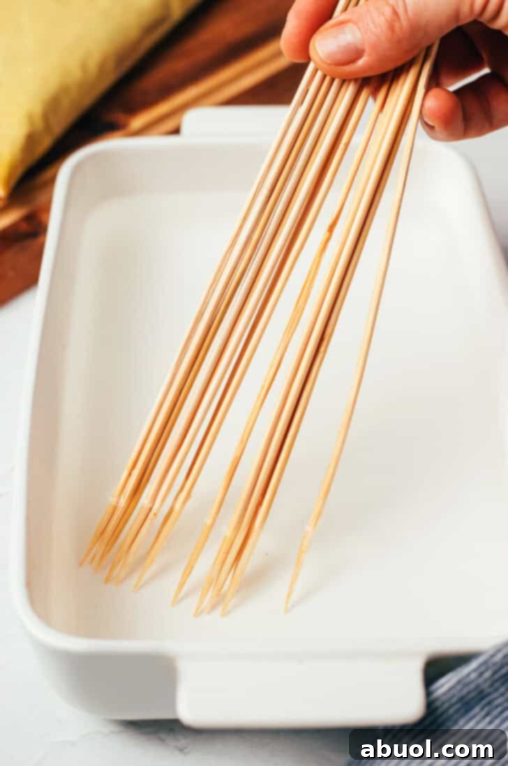 Soaking a handful of wood skewers in water in a white rectangle baking dish.