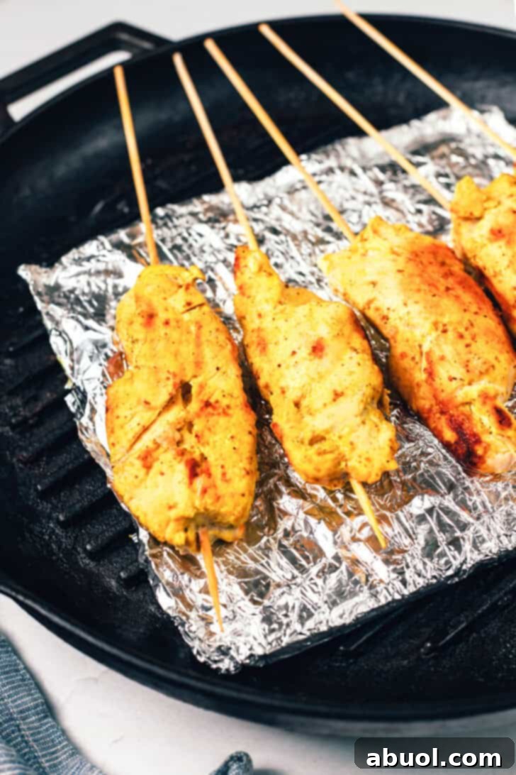 4 grilled chicken skewers resting on a baking sheet coated with foil.